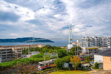 Obraz premium 兵庫県神戸市 明石海峡大橋と淡路島をバックに海沿いを走る山陽電車の風景