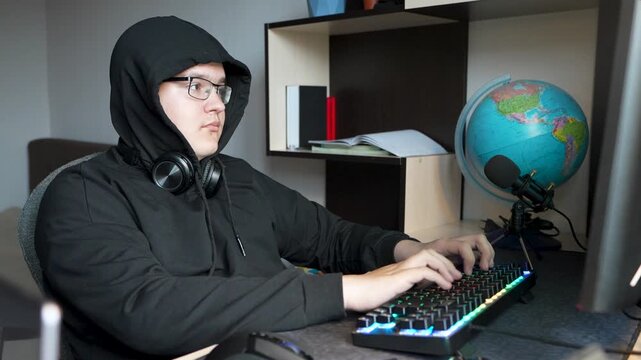 A serious, intense teenager types on a keyboard, programming or hacking into a system with focus and determination.