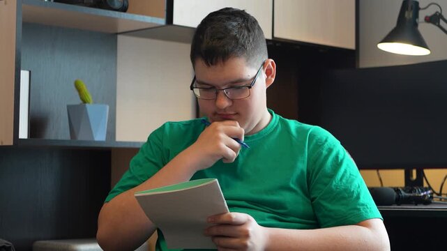 teen boy doing homework for school at home in his room