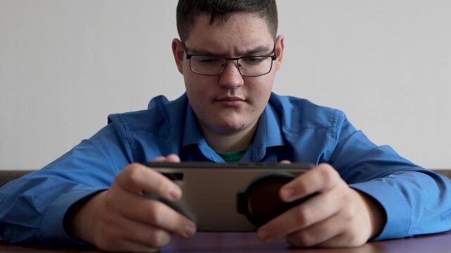 A teenager in glasses looks at his smartphone with surprise, reacting to an unexpected message or shocking online content.