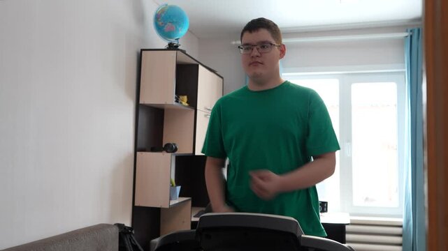 A teenager walks on a treadmill, exercising indoors.