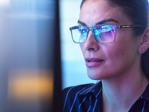 Businesswoman wearing glasses focusing on computer screen with AI data