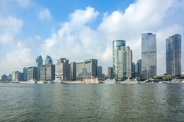 Fototapeta premium Modern Skyscrapers Along Urban Waterfront with Clear Blue Sky