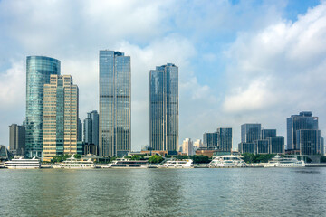 Fototapeta premium Modern Urban Skyscrapers Along Riverbank with Boats