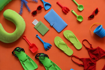 Summer composition with travel pillow, flippers, beach toys, passport and flip-flops on orange background © Pixel-Shot