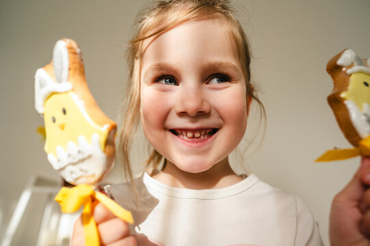 Smiling child holding Easter bunny and chick cookies indoors