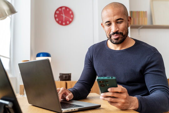 Smiling man using laptop and mobile phone for online learning success