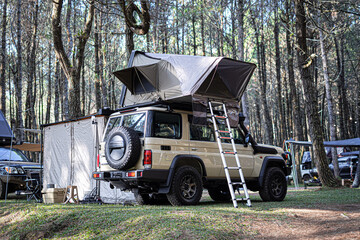 Overland 4x4 vehicle with rooftop tent camping in forest © Tino Nugroho