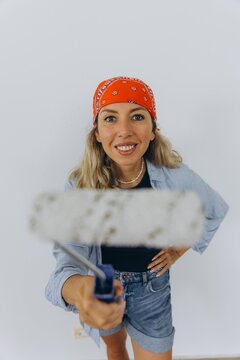 Smiling woman repainting wall during home renovation with paint roller