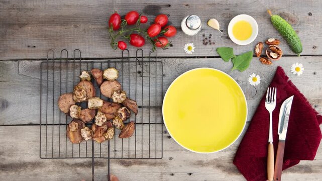 A grill with fried potatoes and zucchini was placed on an old wooden table. Cucumber, tomatoes, spinach, walnut, garlic clove, pepper, oil, and salt were on the table.