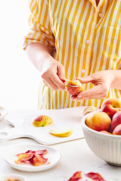 woman hands holding a peach and cutting it with a knife in a white background