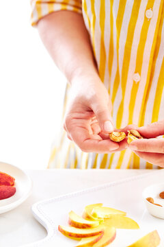 woman hands cutting a peach pit on a white background.