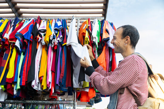 Smiling adult browsing sports fashion at second hand flea market