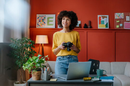 Photographer working in a modern and colourful studio office with a camera and laptop