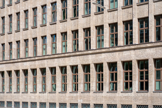 Stone architecture facade with windows on urban building creating symmetry pattern and minimal grid structure with clean texture and geometric repetition