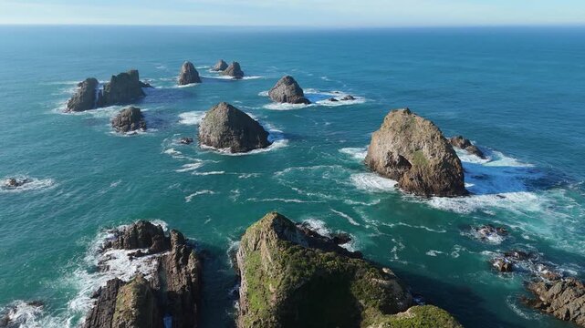 Aerial drone view of Nugget Point coastal rock formations and turquoise ocean in Otago New Zealand