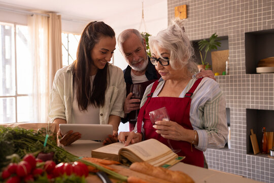 Family cooking together in kitchen with recipe book and fresh ingredients