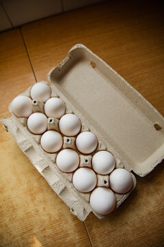 Organic white eggs in carton tray on wooden kitchen surface
