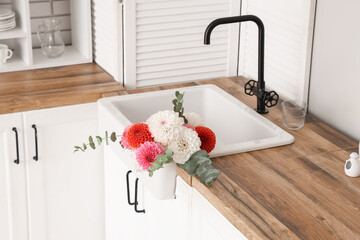 Bouquet of beautiful dahlia flowers in sink on kitchen counter