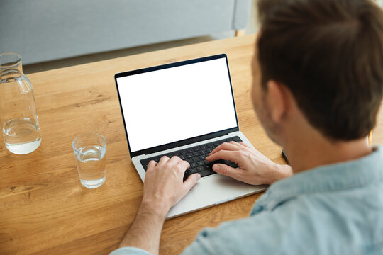 Person typing on laptop with blank screen at home desk