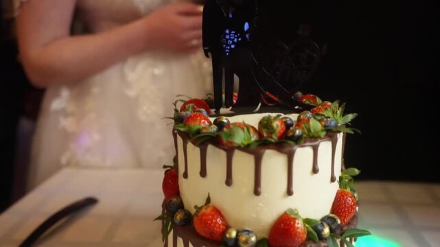 A delightful, lush two-tiered white cake, generously topped and layered with a colorful mix of fresh berries, cherries, and orange physalis