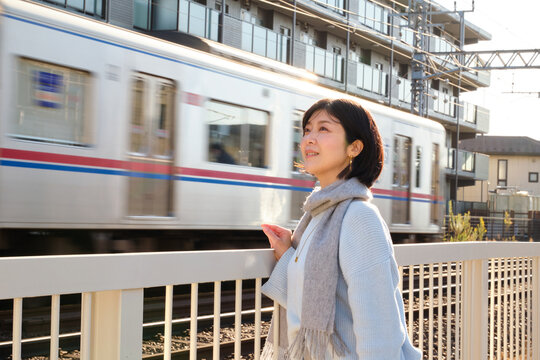 Woman watching a train pass by outdoors on a sunny day in the city