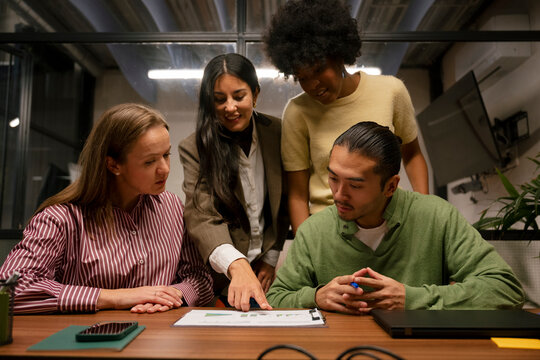 Team collaborating and analyzing charts during business meeting in office