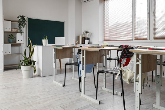 Interior of empty classroom with school desks and greenboard