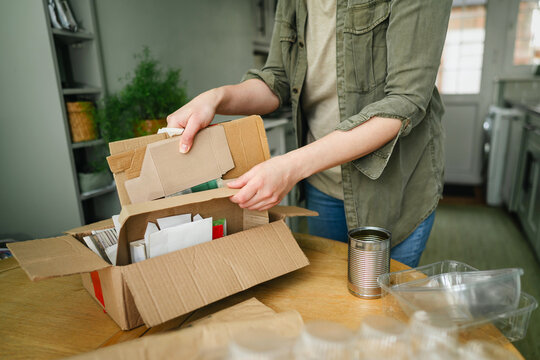 Woman sorting cardboard for recycling in kitchen at home