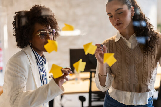 Businesswomen brainstorming and planning with sticky notes in office