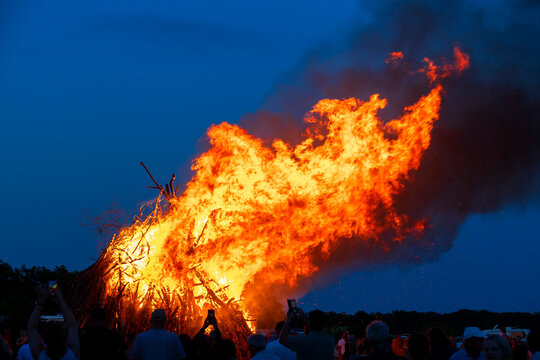 Large solstice bonfire burning outdoors at night
