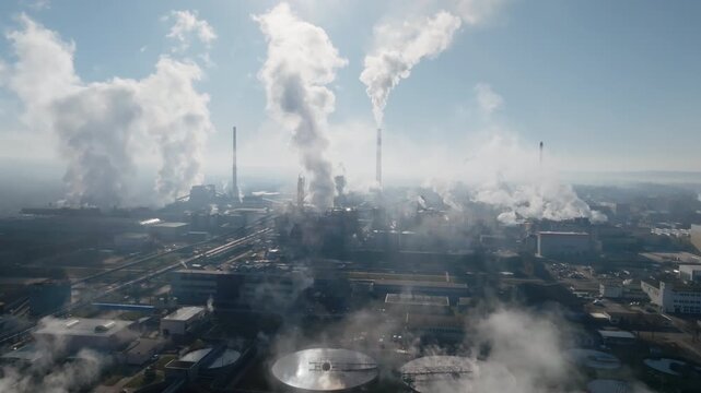 Drone shot capturing dense steam clouds billowing above the &Scaron;tět&iacute; paper mill, with long industrial buildings and networks of roads and pipes below.