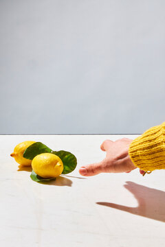 female hand reaching to grab lemons
