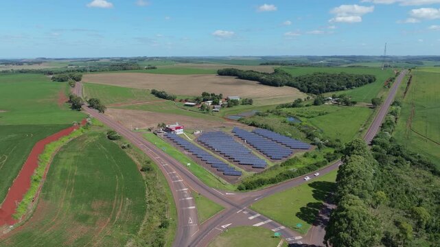 Solar farm aerial over rural road junction surrounded by crop fields and countryside energy infrastructure. Captured in D-Log with 10-bit color using a Hasselblad sensor.