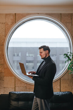 Businessman using laptop in modern office loft with round window