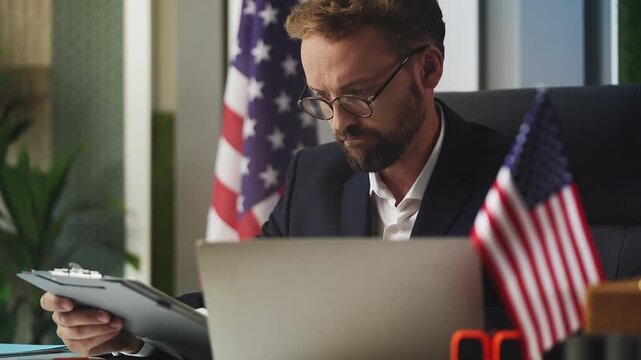 Male embassy employee of U.S. reviewing visa application, talking with candidate
