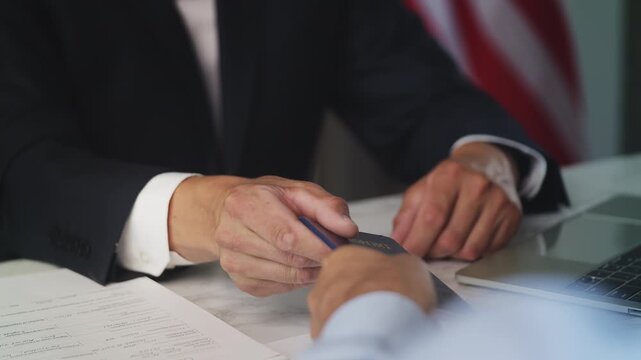 Close-up of embassy worker handing U.S passport to man, processing application