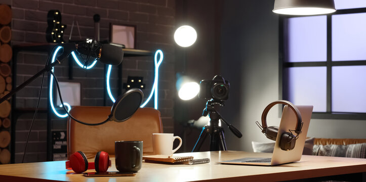 Interior of podcaster's studio with workplace and glowing lamps at night