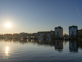 Fototapeta premium Turnhout, Antwep, Belgium, March 1st, 2026, Sunset reflection on waterfront with modern apartments and boats in Turnhout, Belgium