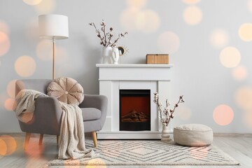 Naklejka premium Grey armchair, fireplace and vases with cotton flowers near white wall in interior of living room