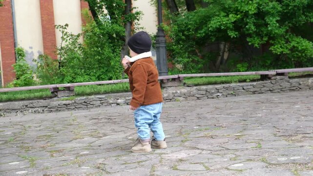 Toddler in jacket on stone courtyard