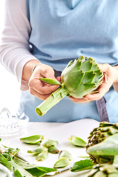 woman peeling an artichoke in a kitchen setting
