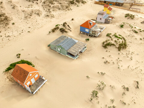 Costa da Caparica, Portugal - 18 December 2024: Aerial view of colorful houses nestled amidst the pale sands, creating a striking contrast of textures and tones.