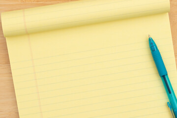 Yellow legal pad with blue pen on desk