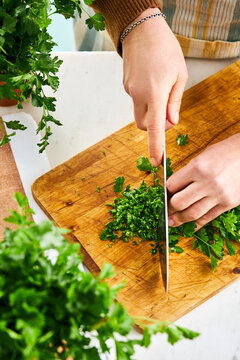 woman hands finely chopping parsley on a cutting board