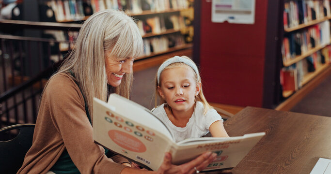 Grandmother, reading book and girl in library, storytelling and bonding together for child development. Senior woman, kid or support for education, literacy and hobby with family and english language