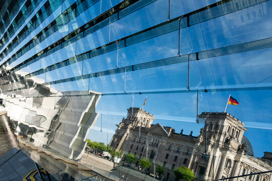 Glass facade reflection in Berlin Germany showing Reichstag landmark architecture as modern distortion with abstract lines and strong daylight contrast