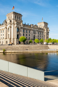 Daylight view of the Reichstag architecture landmark beside the Spree river in Berlin Germany showing parliament presence with bright reflection