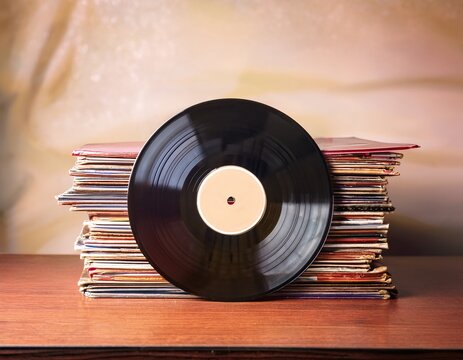 vintage vinyl record on stack of album covers in warm lighting