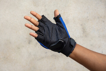Close-up shot of a human hand wearing a black and blue half finger protective glove for motorcycling or cycling. Great for sports safety concepts, biker gear display, and outdoor activity themes.